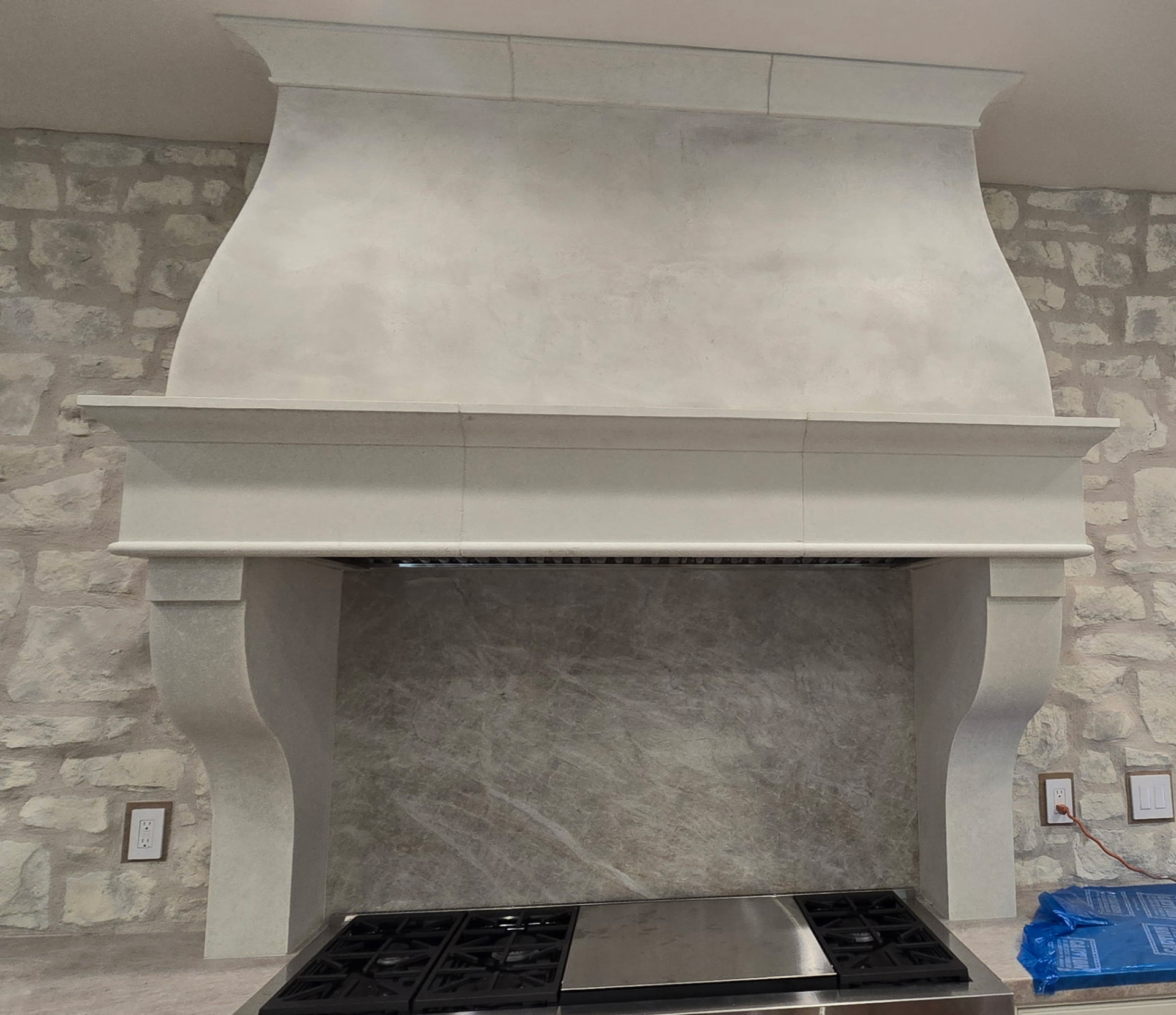 Custom plaster range hood finished to look like carved limestone above a range